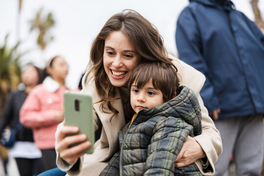 Smiling mother takes a selfie with her toddler son outdoors