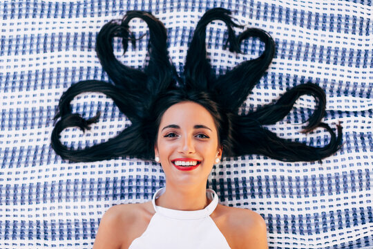 Beautiful woman lying on blanket with heart-shaped hair