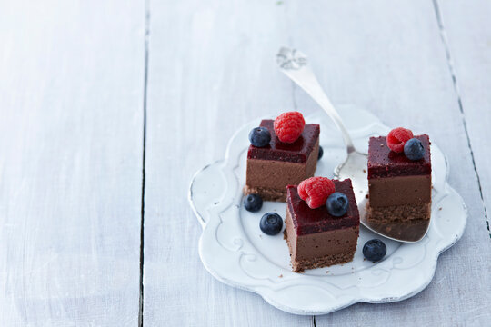 Choco cheesecakes with raspberry and blueberry on plate, close up