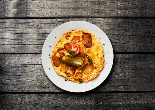 A traditional German potato omelet sits on a dark wooden table