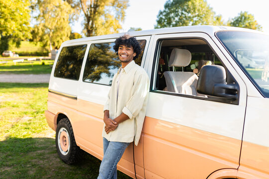 Happy man leans against a camper van outdoors enjoying vanlife