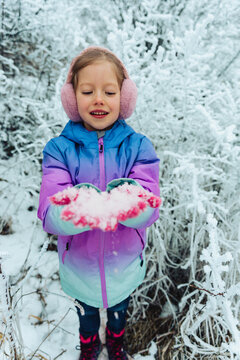 A girl holds fresh snow outdoors during her winter vacation