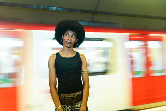 Stylish nonbinary person waits on a subway platform in Barcelona