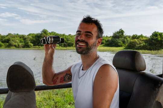 Smiling explorer with binocular in jeep on safari near Sigiriya