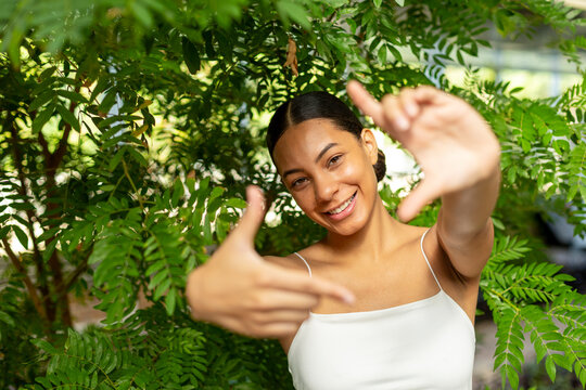 Smiling woman making finger frame gesture outdoors in nature