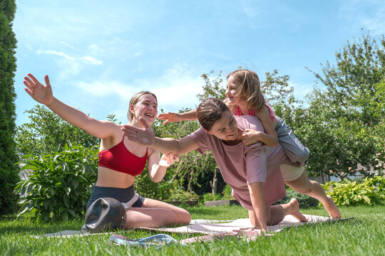 Happy family enjoys outdoor fitness and playful exercise in the garden