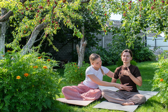 A therapist guides a woman through somatic breathwork in a garden