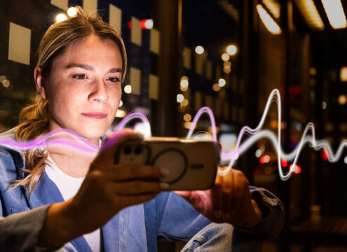 Woman uses smartphone with AI light waves in city at night