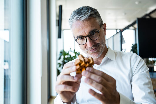 Mature businessman holding a wooden puzzle in the office