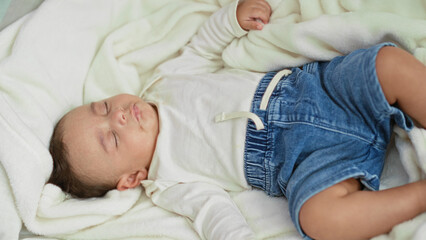 Baby boy sleeping on white fleece blanket, wearing denim shorts, lying on a soft bed inside a bedroom building  innocence serenity. © Krakenimages.com