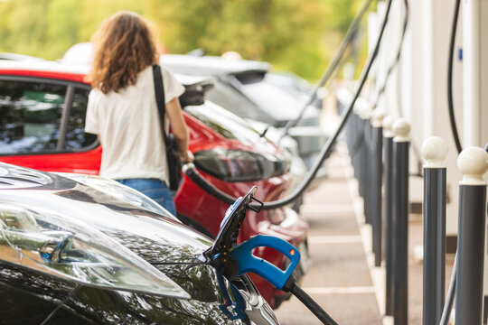 Electric vehicles charging at modern station with cables, eco friendly cars, sustainable transport and green urban mobility lifestyle