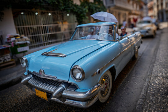 Ein hellblauer Oldtimer f&auml;hrt Touristen durch die Altstadt von Cartagena in Kolumbien