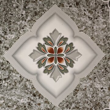 This appears to be a glazed ceramic or porcelain floor tile featuring a speckled gray granite-look base with a centered, vintage-inspired quatrefoil medallion and a rust-brown and sage-green floral.
