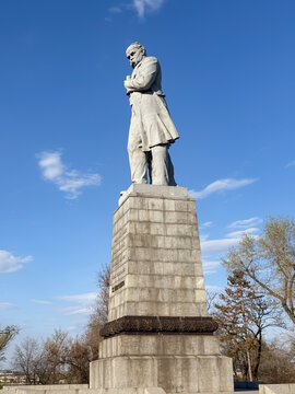 Taras Shevchenko monument rising on a tall stone pedestal against a blue sky in an outdoor park setting, Dnipro, Ukraine - April 6, 2026
