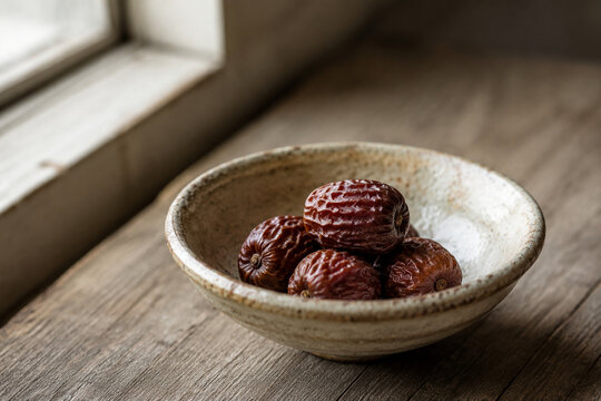 Dried oleaster fruits in a rustic ceramic bowl with soft window light.