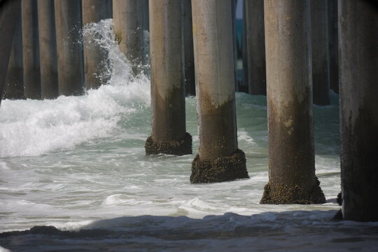 Ocean waves breaking on the beach pier pylons