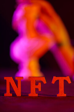 NFT text in red letters on dark background with blurred colorful neon lighting effect