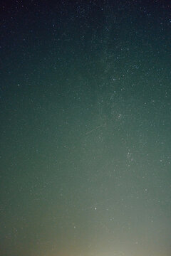 Wide view of clear night sky filled with countless tiny white stars over deep blue to teal gradient background, gentle brightness variation creates calm celestial atmosphere and quiet sense of vast