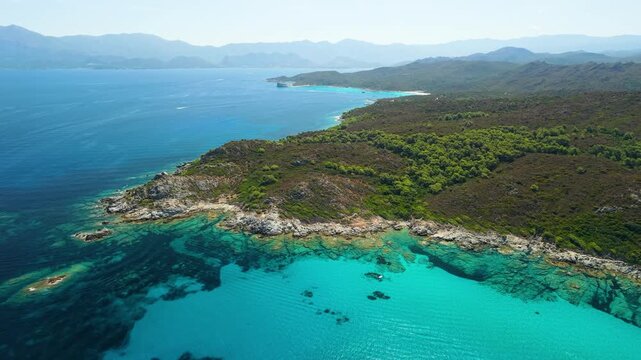 Saleccia Beach Agriates Corsica 4K drone video. Panning view over turquoise bay and pine forest with passing speedboats leaving wakes. Scenic Mediterranean nature reserve travel b roll stock footage