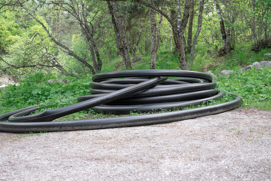 High-quality professional stock photography showcasing a heavy-duty flexible plastic conduit roll integrated into a green forest environment. Infrastructure development, pipeline construction