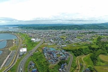 Obraz premium Aerial drone photo of coastal town with wind turbines and harbor in Rumoi, Hokkaido, Japan