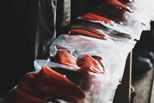 Rows of vacuum‑sealed red salmon fillets rest on a table in soft light, showing freshness and preservation after fishing on an Alaskan river.