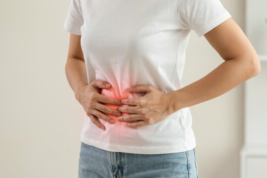 Woman holding her stomach with both hands, experiencing abdominal pain or discomfort