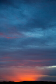 A quiet desert sunrise beneath a deep blue evening sky