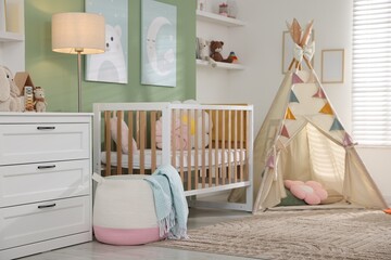 Cute baby room interior with comfortable crib, wigwam and other toys © New Africa