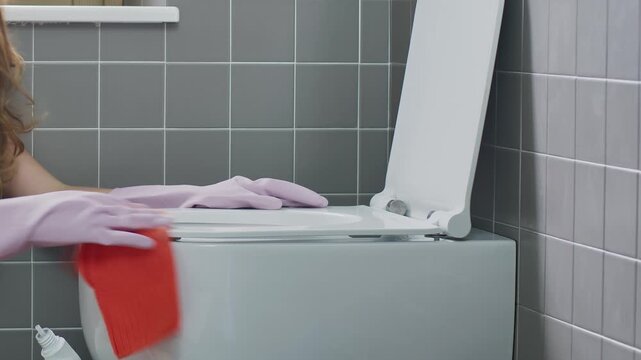 Close Up Hands using a detergent disinfectant bottle and Wiping Toilet Seat