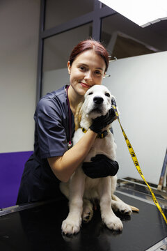 Portrait of pleased female doctor embracing adorable dog on leash