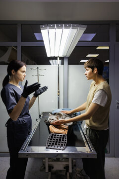 Side view of veterinary doctor talking to owner caressing her cat