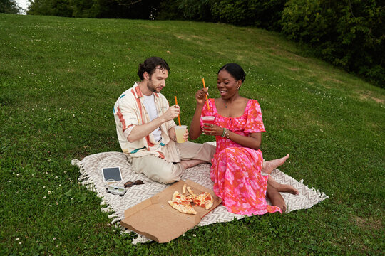 Couple enjoys pizza and drinks on a picnic blanket