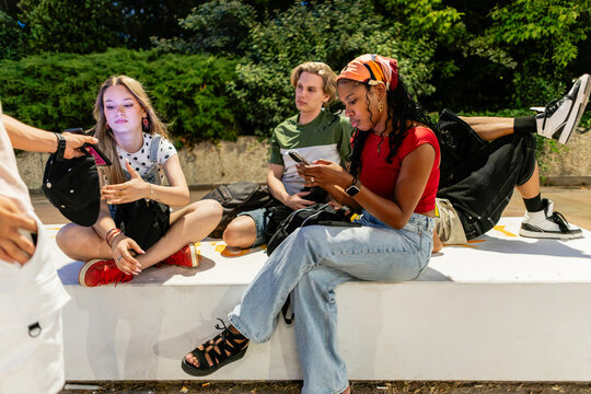 Young people connecting with smartphones in urban park