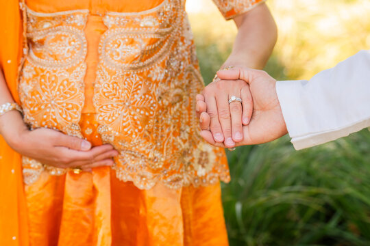 pregnant married couple indian dress wedding ring holding hands