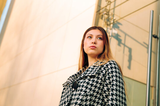 Young businesswoman in houndstooth coat looks upward