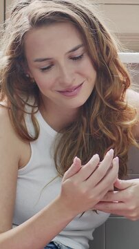 Close-up of smiling young woman using smartphone in bright room