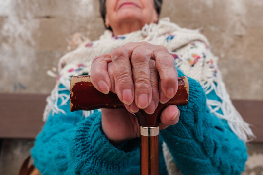 Senior woman holding walking stick handle with wrinkled hands
