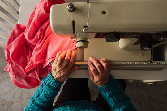 Senior woman's hands sewing fabric with vintage machine at home