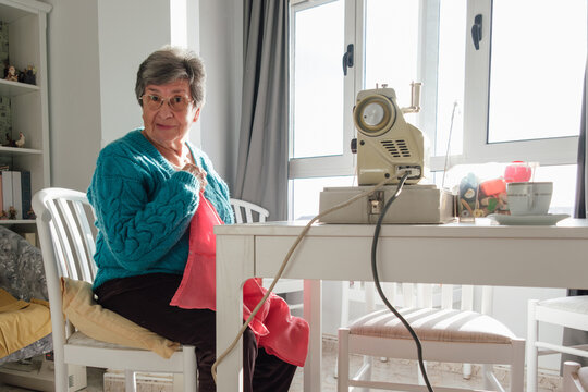 Senior woman enjoying home hobby machine knitting