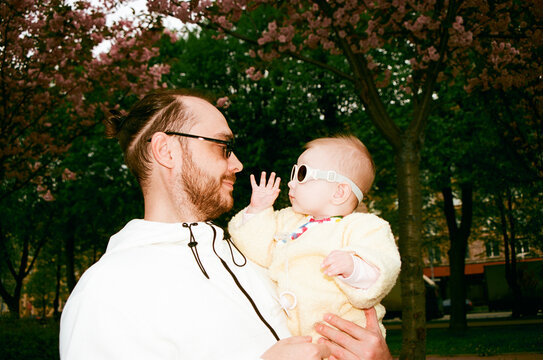Father holds baby under blooming trees