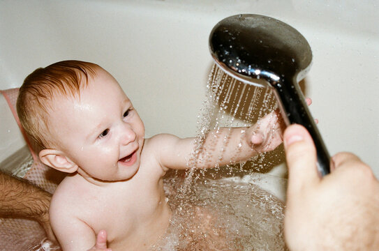 Baby enjoys bath time with water and smiles