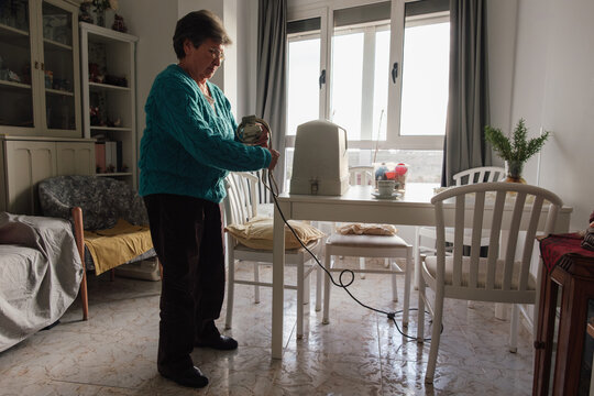 Senior woman preparing machine knitting for hobby at home