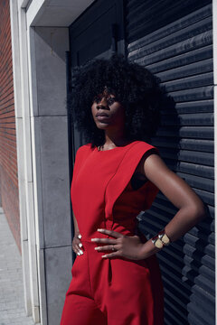 Model poses in red outfit against dark background