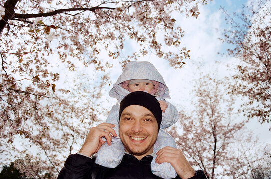 Father carries baby on shoulders during spring day