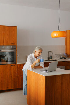 Woman working on laptop computer in kitchen