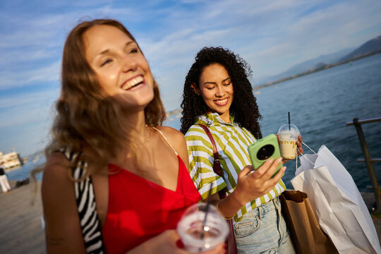 Young women friends shopping enjoying summer day by sea