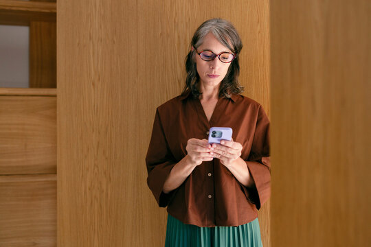 Businesswoman Using Smartphone in Wooden Interior