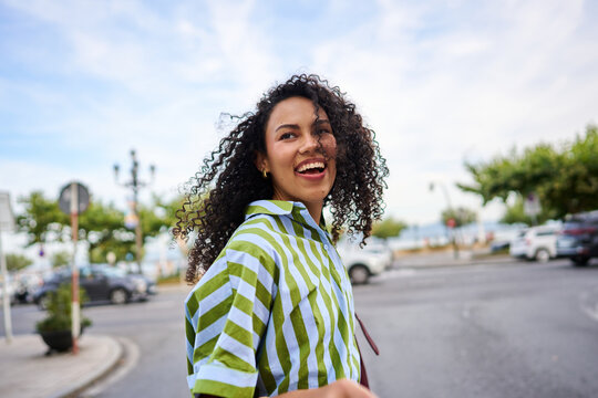 Young woman with curly hair smiling on urban street