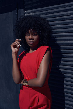 Model poses in red outfit near black wall